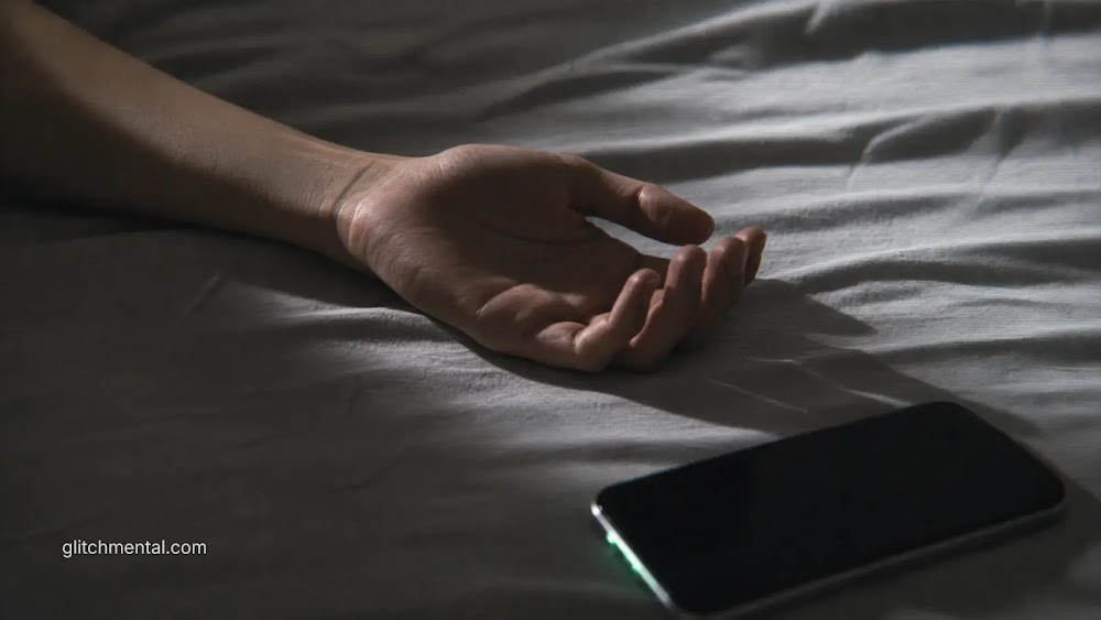 detox digital: smartphone apagado junto a una mano sobre la cama
